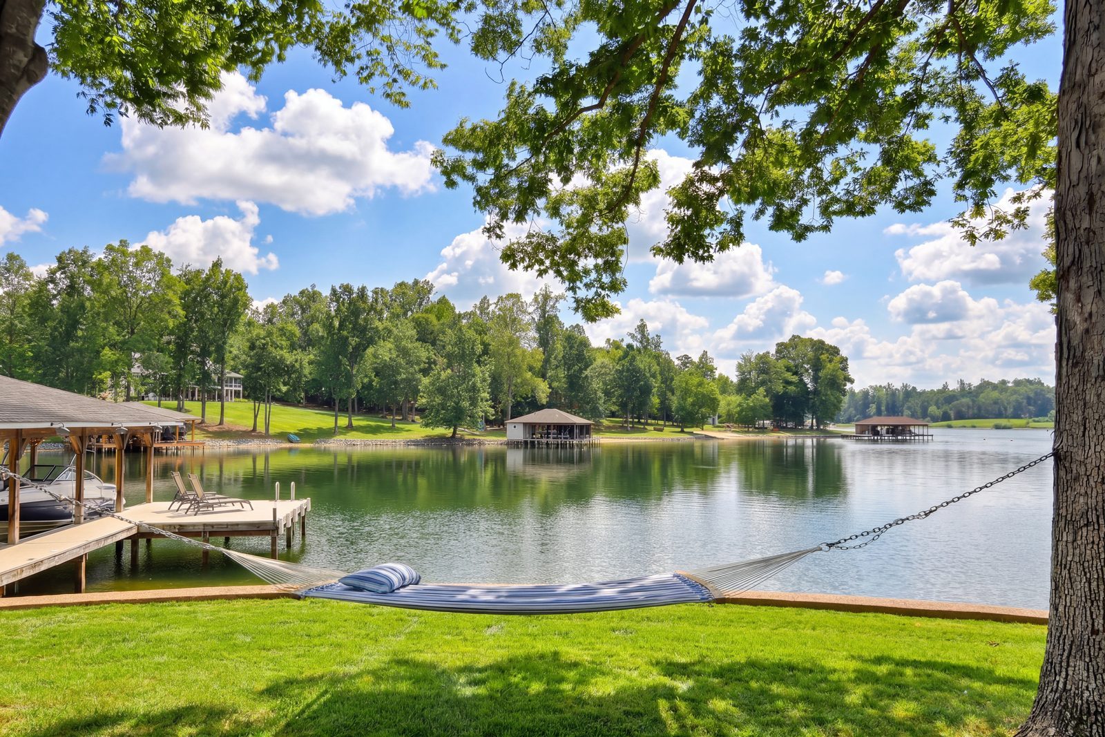Hammock under a shade tree overlooking the dock and calm lake